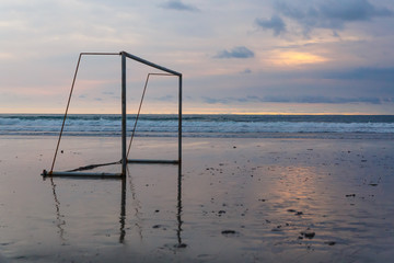 Football gate on the ocean beach at sunset.