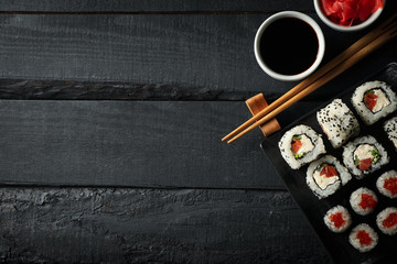 Tray with delicious sushi rolls on wooden background, top view. Japanese food