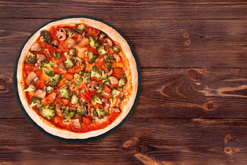 Pizza with veggie vegetables on slate bottom, on wooden table top view, space for text
