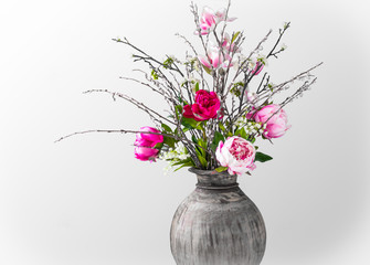 Wild modern spring bouquet with pink peonies, magnolia branches, May bells and willow catkins on a white  background. Close-up.