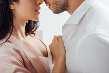Cropped view of woman unbuttoning male shirt