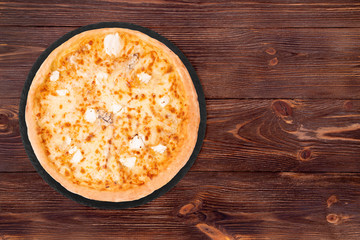 Pizza five cheeses on slate bottom, on wooden table, top view, space for text