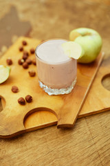 Yogurt with apple and nuts on a wooden background. Daylight.