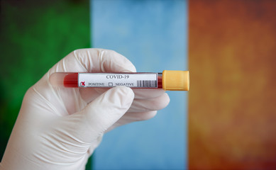 COVID-19 Pandemic Coronavirus concept ; Close-up of a Positive COVID-19 blood test sample tube with Flag of Ireland at background. Blood testing for diagnosis new Corona virus infection.