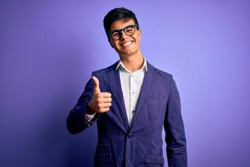Young handsome business man wearing jacket and glasses over isolated purple background doing happy...
