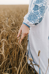 Country, nature, summer holidays, agriculture and people concept - close up of young woman hand touching spikelets in cereal field