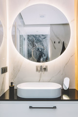 Modern sink and round mirror with led light in a luxury bathroom - obrazy, fototapety, plakaty