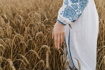 Country, nature, summer holidays, agriculture and people concept - close up of young woman hand touching spikelets in cereal field