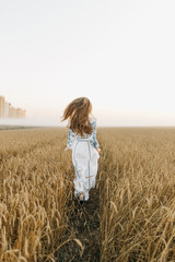 Girl in a wheat field, view from the back