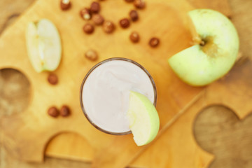 Yogurt with apple and nuts on a wooden background. Daylight.