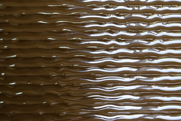 Glare of light moves along the surface texture. Volumetric texture waves on a brown smooth...