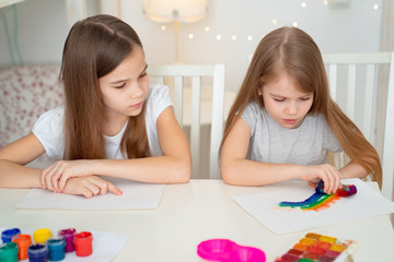 Obraz na płótnie Canvas two sisters drawing rainbow. stay at home.
