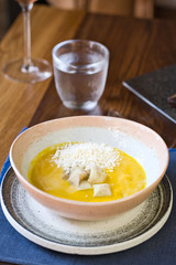 Yellow cream soup with croutons on a served table 