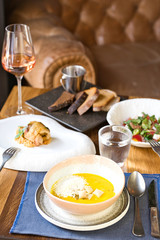 Cafe table served with cream soup, vegetable salad and chicken roll with a glass of wine and water