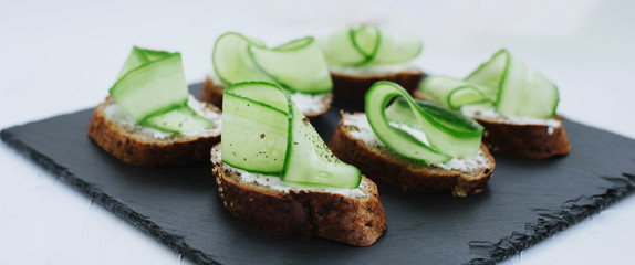 Dietary traditional open sandwiches with baguette and cucumber on a white background. Banner for website