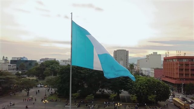 An aerial shot of the historic Parque Centenario in Zone 1 of Guatemala city with the national flag waving at golden hour. 