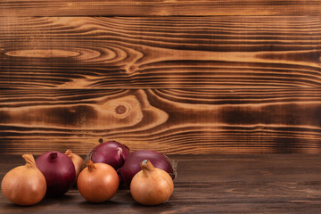Unpeeled raw yellow and purple onions on a wooden surface. Fresh vegetables, healthy organic food