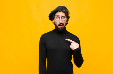 young french artist man looking shocked and surprised with mouth wide open, pointing to self...