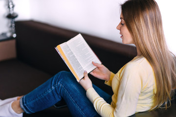 Obraz premium woman lying on sofa and reading book at home