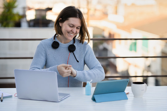 Female working remotely at home terrace with laptop and headphones
