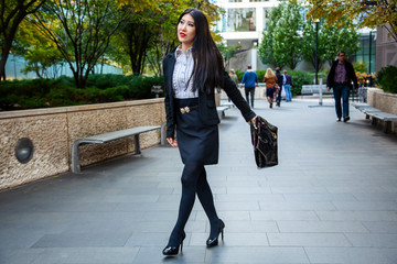 Beautiful Chinese Asian woman in fashionable business attire is enjoying a nice day walking around...