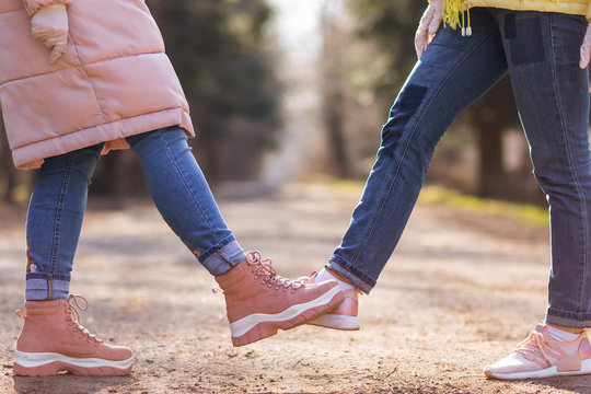 Foot tap. New novel greeting to avoid the spread of coronavirus. Two women friends meet in park. Instead of greeting with a hug or handshake, they touch their feet together instead.