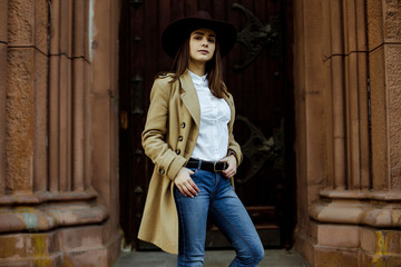 Attractive young woman in fashionable coat and hat posing on the street 