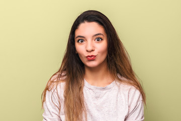 portrait of cheerful young woman brunette with big eyes with black eyeliner making funny face against yellow background