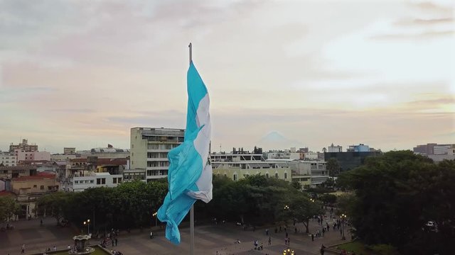 An aerial shot of the historic Parque Centenario in Zone 1 of Guatemala city with the national flag waving at golden hour. 