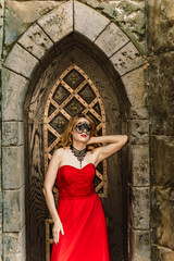 A woman in a red dress stands on a background of a medieval castle