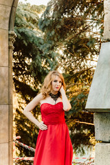 A woman in a red dress stands on a background of a medieval castle