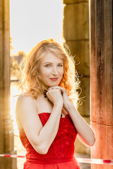 A woman in a red dress stands on a background of a medieval castle