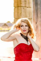 A woman in a red dress stands on a background of a medieval castle