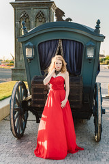 A woman in a red dress stands on a background of a medieval castle