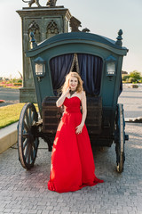 A woman in a red dress stands on a background of a medieval castle