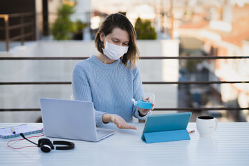 Female working remotely at home terrace with laptop and headphones