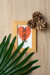 Lifestyle picture. Wooden table with decorative frame, brown pine cones and palm tree leaf. Cosy style. Top view, flat lay.