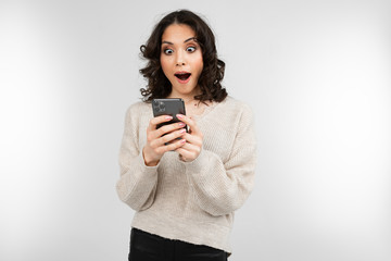 surprised brunette girl in a white sweater with a phone in his hand on a white background with copy space