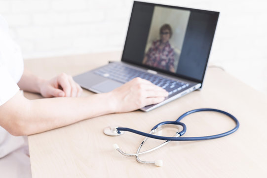 gp hosts an online appointment with an elderly quarantined patient at home. Female doctor at the desk talking to an elderly woman on a web camera and gives treatment recommendations