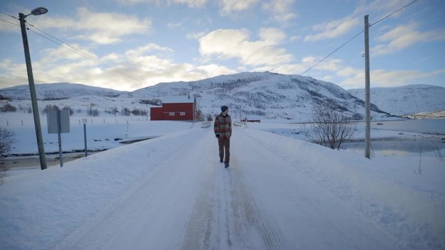 A Man Walking Down an Empty Snow Covered Road in a Cold Winter Environment, Static Slow Motion
