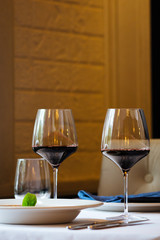 Side view on served table in italian restaurant with a dish in a plate and glasses with red wine, horizontal format