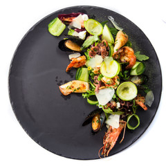Top view isolated delicious restaurant seafood salad with vegetables on the black plate