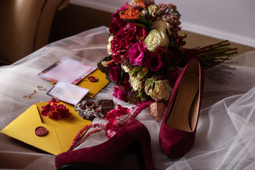 wedding accessories: a bride’s bouquet of roses, peonies and hydrangeas, wedding rings on a...