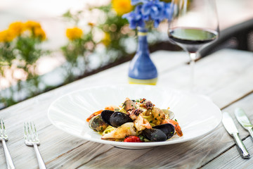 Closeup on appetizing italian cuisine restaurant  dish seafood pasta on the white wooden table with yellow flowers on the background, horizontal format