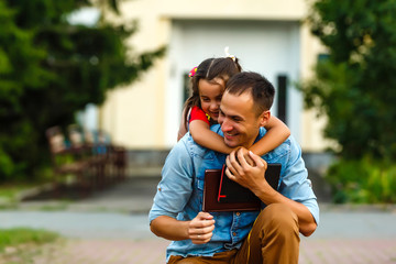 first day at school. father leads a little child school girl in first grade
