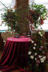 round table with a red tablecloth surrounded by floral arrangements