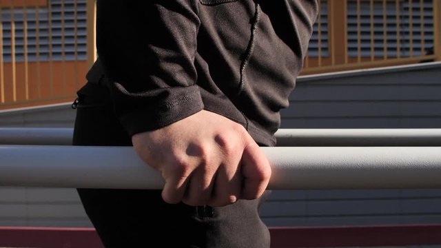 The guy, the athlete trains on the street, performs basic exercises, boxing, push-ups, pulls himself up, looks cool