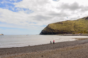 Obraz premium Black sand beach with a beautiful sky practically deserted in San Sebastian de la Gomera. April 15, 2019. La Gomera, Santa Cruz de Tenerife Spain Africa. Travel Tourism Photography Nature.