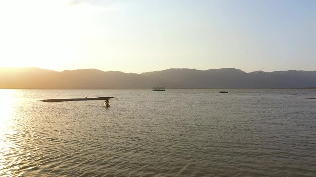 February 29th, 2020 - Perlis, Malaysia : 4k Aerial View of a man fishing at Timah Tasoh Lake side During Beautiful Sunset with scenic Mountain view. Establishing, Drone Rising Forward Shot