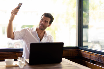 Portrait of happy Turkish man taking selfie at the coffee shop